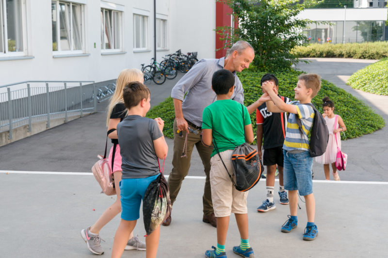 Reportagefotografie: Ein Lehrer bei der Arbeit: Der Lehrer spielt auf dem Pausenhof mit den Kindern.