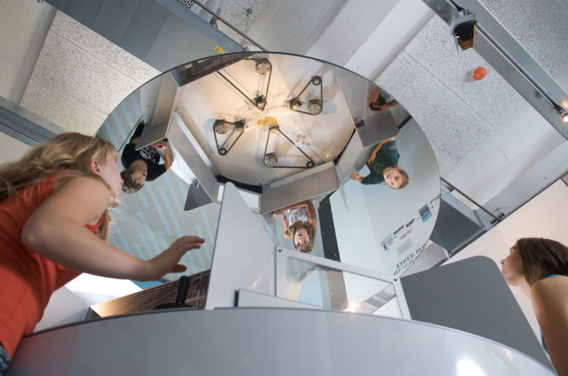 Editorial photography: Learning by playing: Children discover mechanical functions in a game in which you can only see what the others are doing in a mirror on the ceiling. They have to work together in a coordinated way to achieve something together in time.