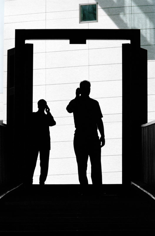 Lifestyle photography: Two men use mobile phones and are shown as a silhouette.