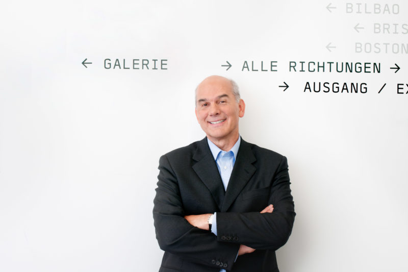 Event photography, editorial photography: Business portrait: Portrait of a manager in the corridor of his company in front of a white wall with signposts.