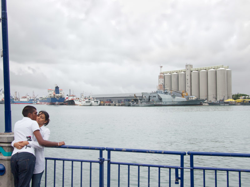 Reisefotografie: Mauritius: Liebespaar an der Pier im Hafen von Port Louis. Im Hintergrund Schiffe der Küstenwache.