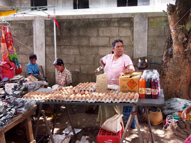 Reisefotografie: Mauritius: Kinder und eine Verkäuferin von Eiern und Getränken an ihrem Stand auf einem kleinen Straßenmarkt.