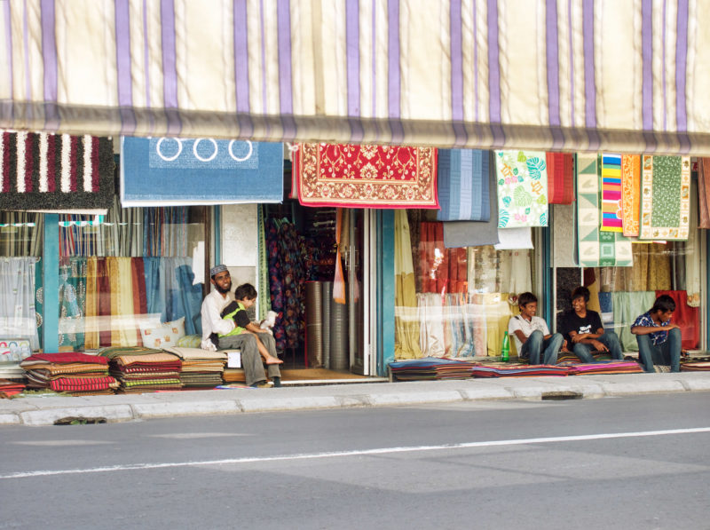 Reisefotografie: Mauritius: Ein Teppich- und Tuchhändler mit Kindern vor seinem Laden.