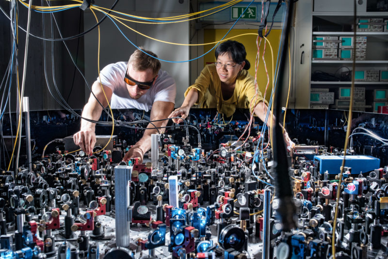 Science photography: 2 employees at a measuring table of the 5th Physical Institute of the University of Stuttgart under the direction of Prof. Dr. Tilman Pfau. The table is covered with optical modules that conduct laser light and sensors that make measurements possible.