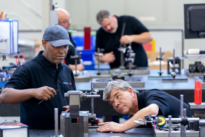 Industriefotografie: Mitarbeiter bei Kontrollmessungen von Bauteilen in der Fertigung von Werkzeugmaschinen.