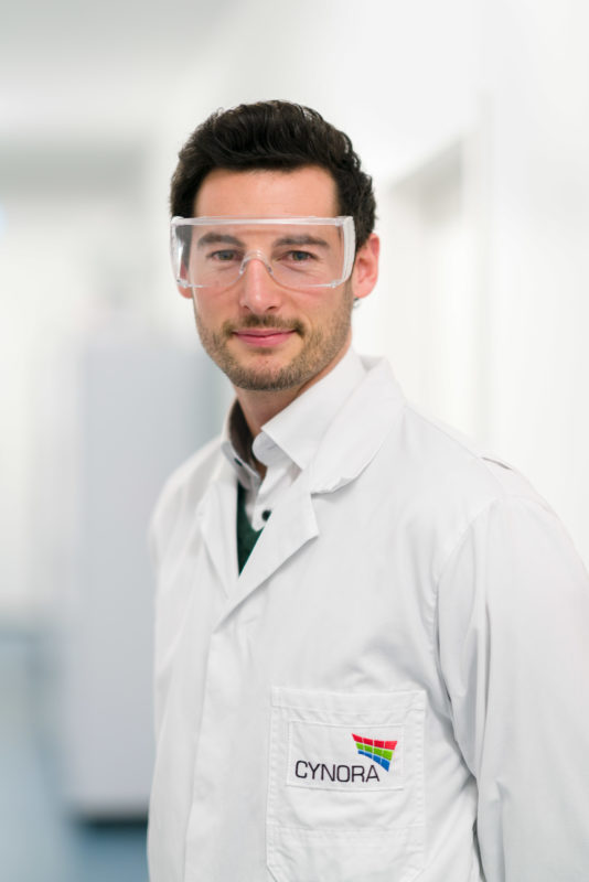 Employees photography:  An employee in the laboratory of a company researching luminescent materials for OLED production. He wears protective goggles.