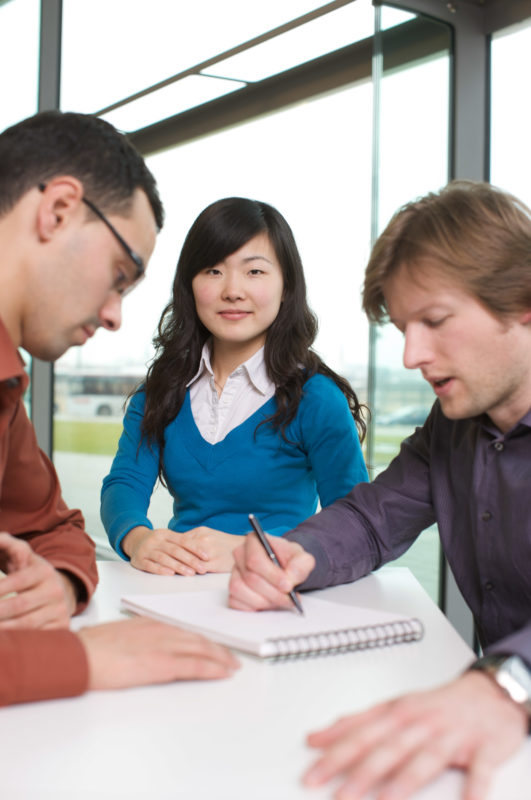 Employees photography: Portrait of a young Chinese employee of a software company in the circle of other colleagues.