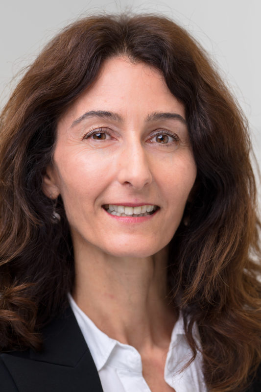 Portrait photography: Portrait of an employee illuminated with studio flash in front of a neutral background. The sharpness is almost exclusively on the eyes of the person by using the fully open aperture of a fast lens.