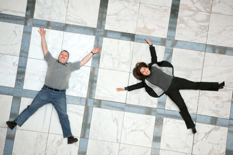 Employees photography: Employees Portrait: Two employees are on the floor laughing and form an X.