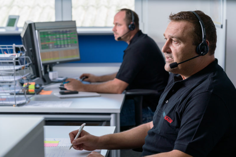 Industriefotografie: Zwei Mitarbeiter mit Headsets in der Hotline eines mittelständischen Maschinenbauers.