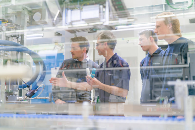 Industrial photography: Four employees at a medium-sized manufacturer of packaging machines discuss details on one of their systems.