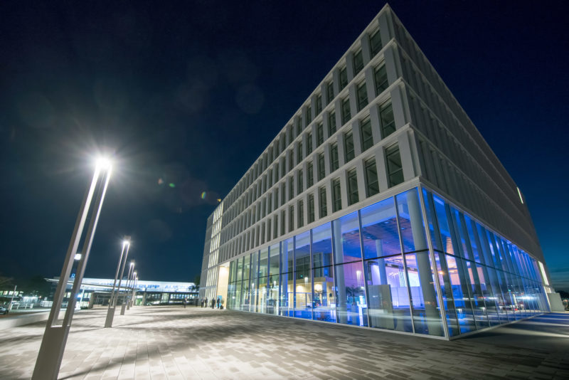 Architekturfotografie: Nachtaufnahme einer im Foyer blau beleuchteten Firmenzentrale von außen.