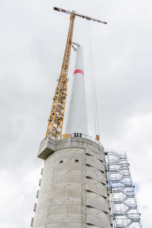 Technikfotografie: Im Bau befindliches Windkraftwerk des Naturstromspeichers Gaildorf. In seinem Sockel befindet sich ein großer Wasserbehälter, der nach dem Prinzip des Pumpspeicherkraftwerks als Einergiespeicher genutzt wird.