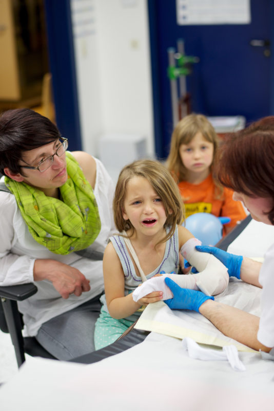 Healthcare photography: A little girl gets a cast around her broken arm in the emergency room of a district hospital. Her mother is trying to comfort her.