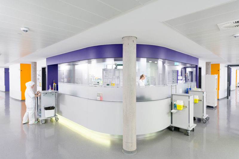 Architectural photography: Modern personnel pulpit on a nursing ward of a hospital. You see two nurses working inside and outside the pulpit.