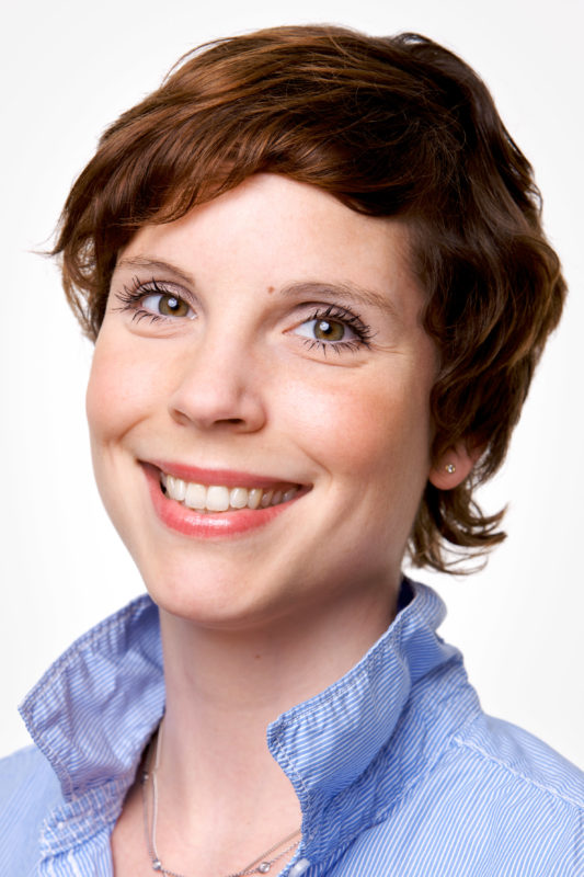 Portrait photography: Employee portrait against a white background. The photo was taken with studio flash in front of a white background. The assembly of the set took place on a corridor in the company.