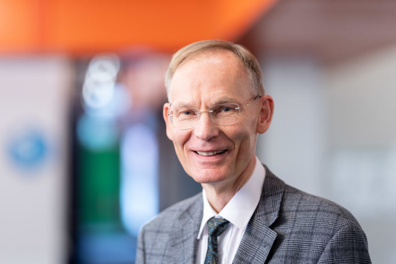 Portrait photography: scientists in their institute building. In addition to the laughter of the person depicted, a colored blurred background creates a positive atmosphere in this portrait