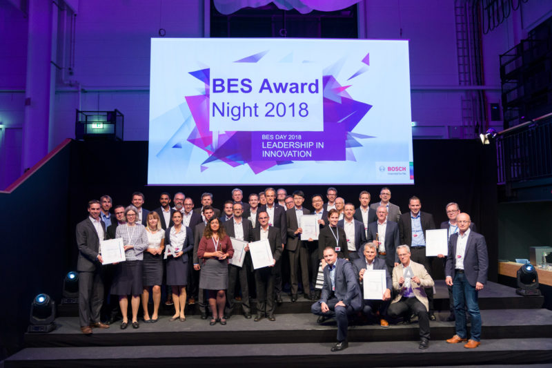 Group photo: After an award ceremony at a company event, all prize winners stand and sit together for a group photo. Above the logo of the event.