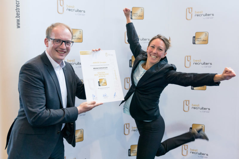 Event photography, editorial photography: After an award ceremony, a winner jumps up in cheers for the press photo, while her colleague holds the award certificate in the picture.