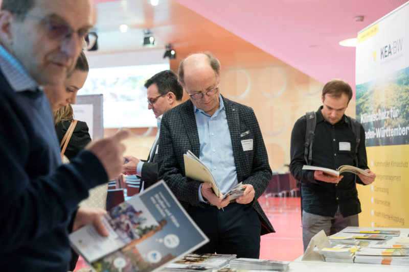 Pressebilder für eine Initiative der Baden-Württembergischen Landesregierung anlässlich der Auftaktveranstaltung des Kompetenznetzes KLIMAMOBIL mit Verkehrsminister Winfried Hermann: Besucher betrachten vor Beginn des Events ausgestellte Unterlagen.