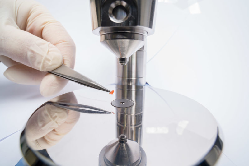 Industry photography: In a test laboratory: In the testing laboratory of a cable manufacturer, fragments of an orange cable sheath are examined.