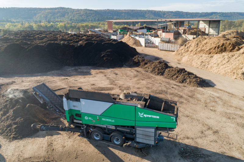 Reportagefotografie: Drohnenaufnahme einer Siebmaschine für Kompostabfälle, die in einem Recyclingunternehmen arbeitet.