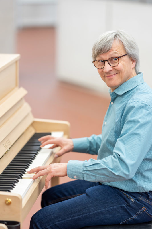 Reportage photography: Scientists create artificial ivory: One of the scientists is playing with pleasure on the piano, whose keys were made of the new material.