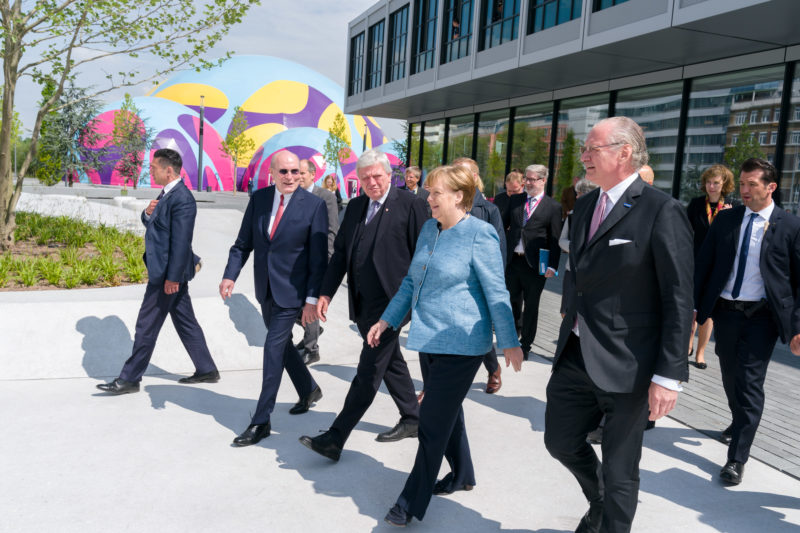 Reportagefotografie: Bundeskanzlerin Angela Merkel auf der Feier zum 350jährigen Jubiläum der Firma Merck in Darmstadt. Die VIP-Gäste gehen zusammen mit ihr zur Firmenbesichtigung. Im Hintergrund das extravagante Festzelt.