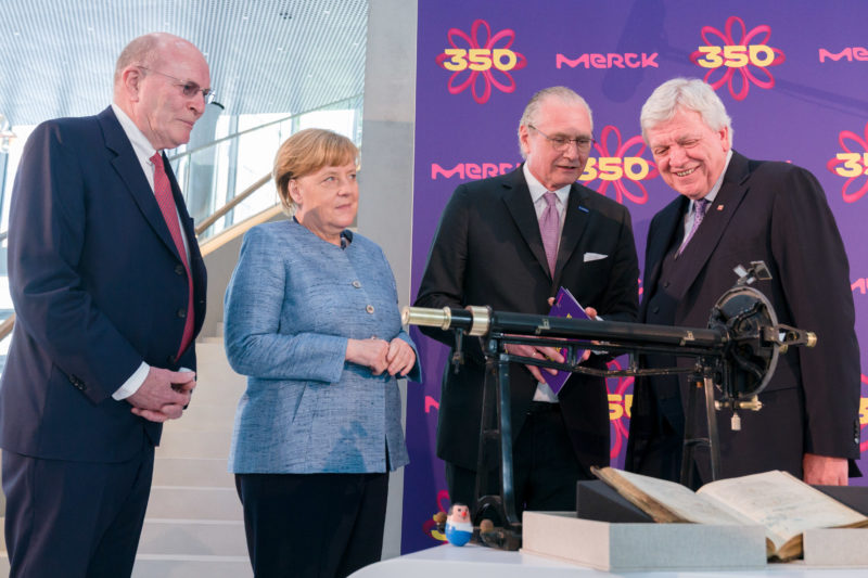 Reportagefotografie: Bundeskanzlerin Angela Merkel auf der Feier zum 350jährigen Jubiläum der Firma Merck in Darmstadt. Zusammen mit Volker Bouffier unterhält sie sich mit den Firmenchefs. Im Vordergrund sieht man Gegenstände aus der Gründergeschichte.