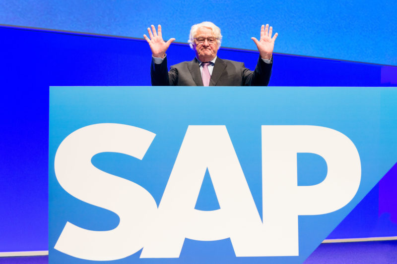 Vorstandsportrait: Vor Beginn der Hauptversammlung der SAP SE zeigt sich einer der Gründer der SAP Hasso Plattner der Presse und den Aktionären. Als Aufsichtsratsvorsitzender führt er die Hauptversammlung. Er steht für ein Pressefoto hinter einem großen Logo der SAP SE auf der Bühne und hebt die Hände zum Gruß.