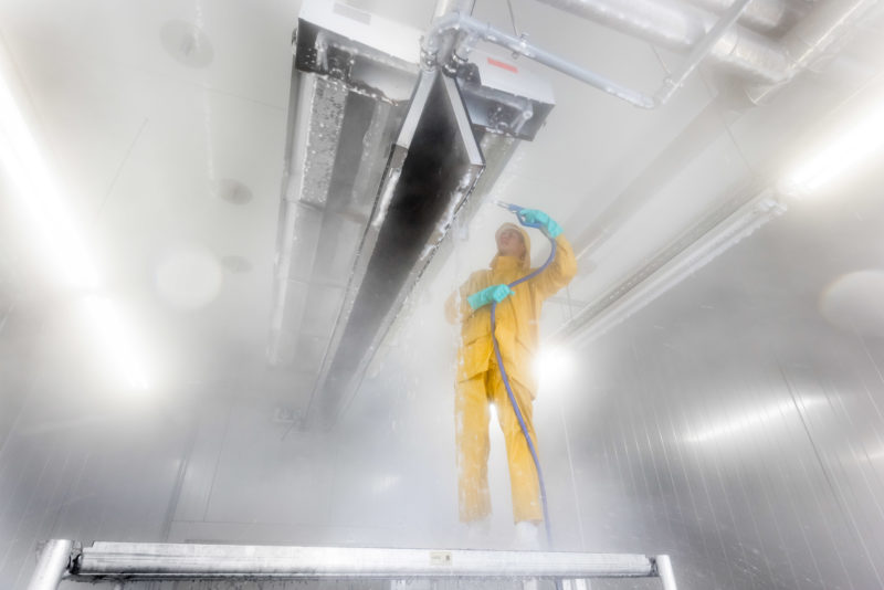 Industrial photography: High pressure cleaning of a large plant of a food manufacturer almost completely made of stainless steel. With special foam every surface is intensively cleaned and disinfected at the same time.