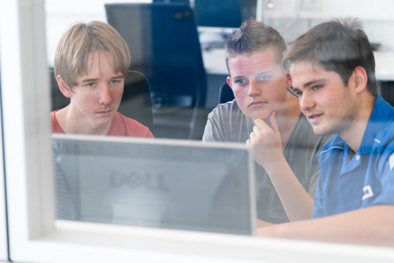 Editorial photography: A trainee explains a computer program to two pupils during an internship. This gives them an impression of the in-company training.