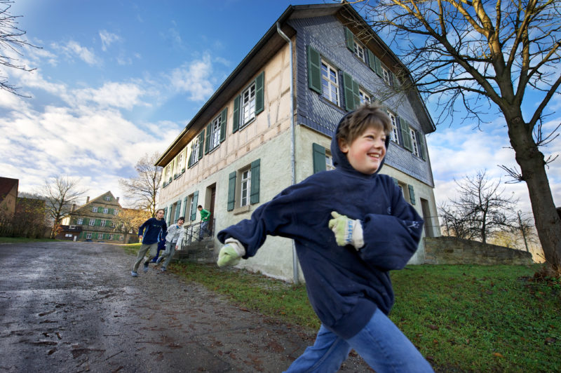 Editorial photography: To pause the lesson children run out of the old school building in the museum. Fresh air is taken for granted.