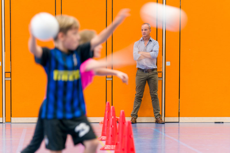 Reportagefotografie zum Thema Lernen und Bildung: Ein Sportlehrer beobachtet seine Schüler beim Völkerball-Spiel.