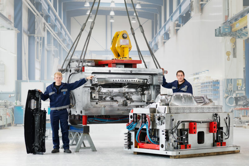 Industriefotografie: Zwei Mitarbeiter in der Fabrikhalle neben ihrem eben fertiggestellten Spritzgusswerkzeug für die Autoindustrie.