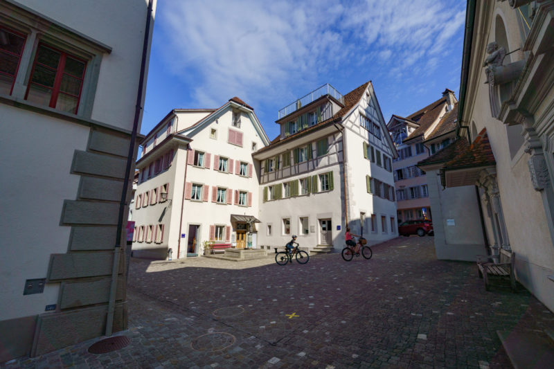 Stadtportrait: Zug am Zuger See. Fahrradfahrer auf dem historischen Kopfsteinpflaster in der verwinkelten Altstadt von Zug.