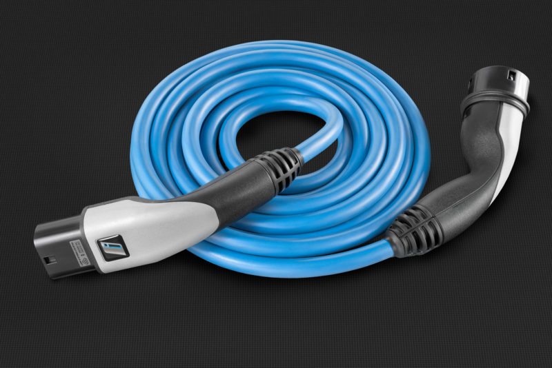 Studio photogaphy: A blue charging cable for electric vehicles. It lies rolled up on a black background. The material illustration emphasizes the surfaces of the plastics used in its manufacture.