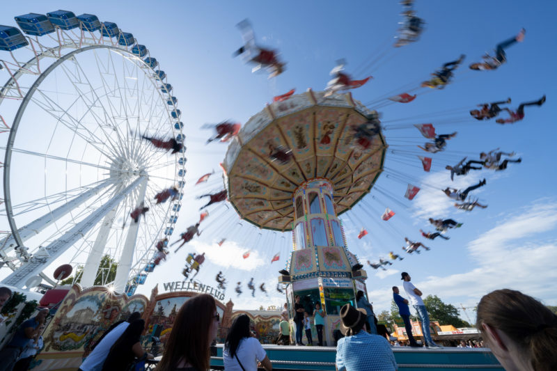 Stadtportrait Stuttgart: Riesenrad und Kettenkarussell beim Volksfest auf dem Cannstatter Wasen. Durch die längere Verschlusszeit scheinen die Besucher durch die Luft zu wirbeln.