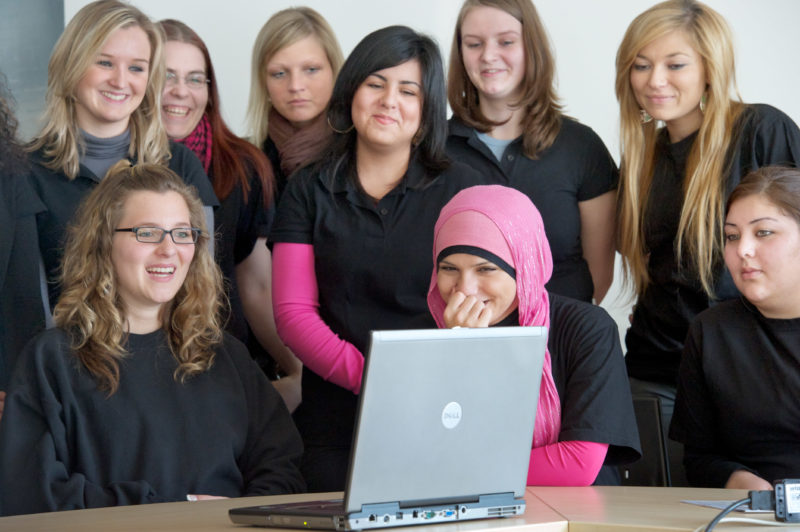 Editorial photography: Apprentices in retail in teaching on the notebook. One of the trainees is Turkish descent and wears a headscarf.