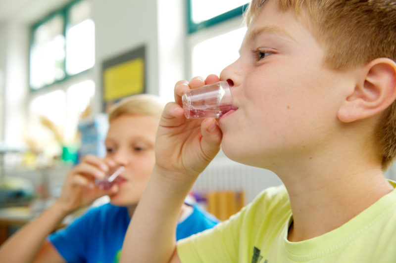 Editorial photography: Children in an elementary school learn through rehearsals from small cups about the need to drink and what drinks are healthy and tasty for them and why.