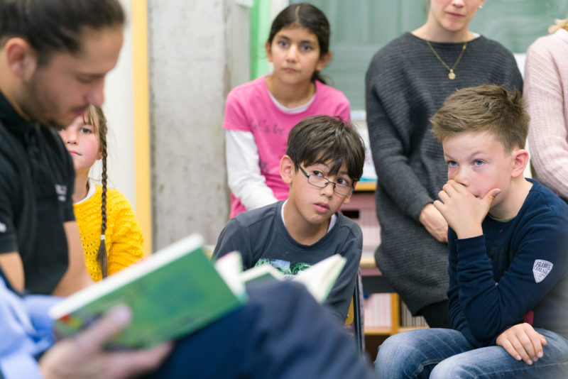 Reportagefotografie zum Thema Lernen und Bildung: Während einer Vorlesestunde an einer Grundschule hören Kinder aufmerksam und nachdenklich zu. 