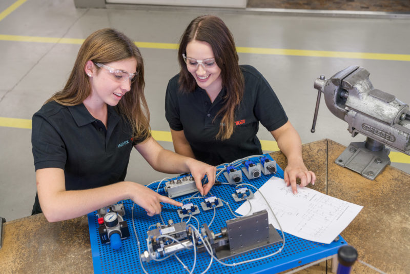 Editorial photography: Two female trainees work together on a hydraulic circuit.