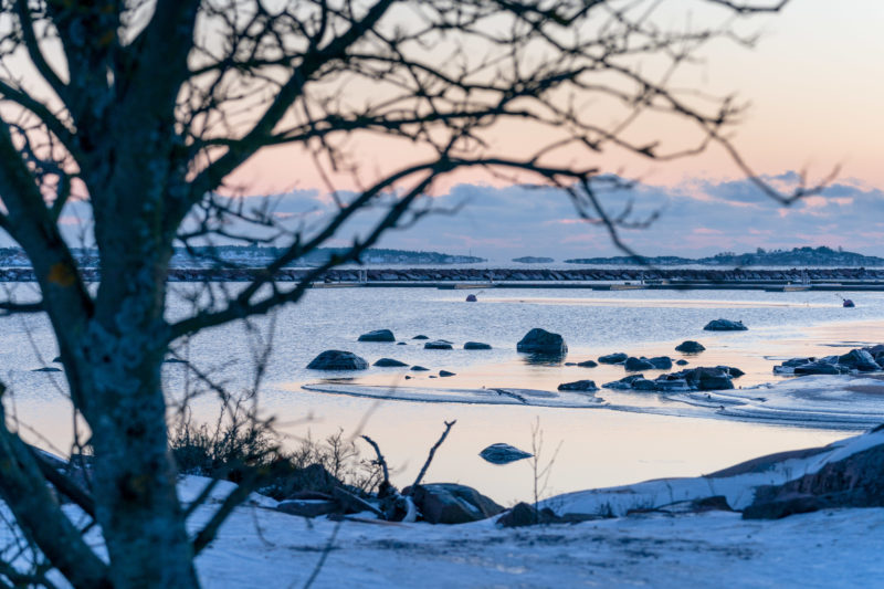 Landscape photography: Winter in Finland: Small islands with polished rocks with snow and ice in reddish diffuse sunlight give a typical winter view of the Baltic Sea coast.