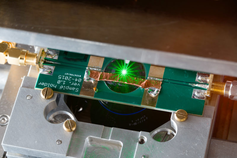 Science photography at a physics institute of the University of Stuttgart: Detail photo of a green laser beam on a sample.