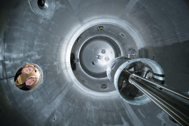 Wissenschaftsfotografie: Forscher blicken durch eine Öffnung in die Wolkenkammer AIDA am Karlsruher Institut für Technologie (KIT).