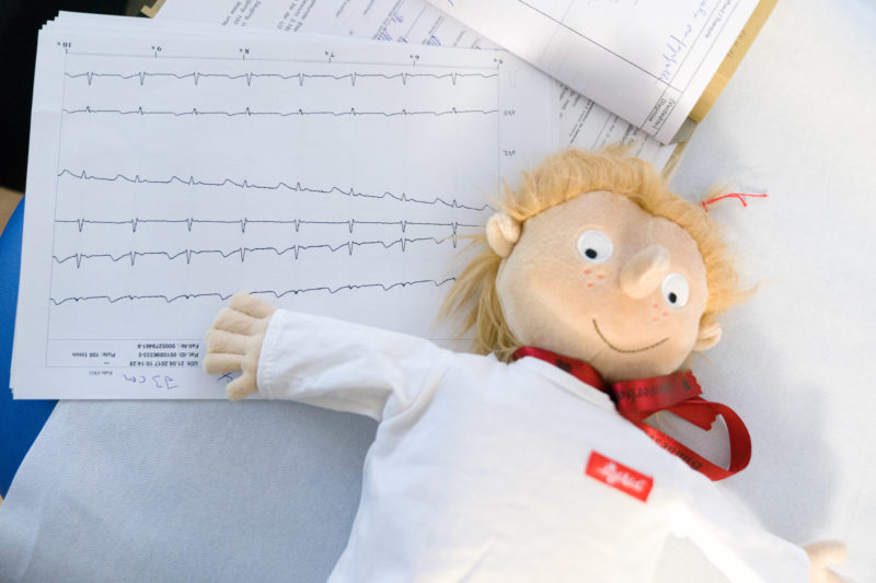 Healthcare photography:  In the pediatric cardiology department of the University Hospital Homburg (Saar) a toy doll is lying on the printouts of an ECG.